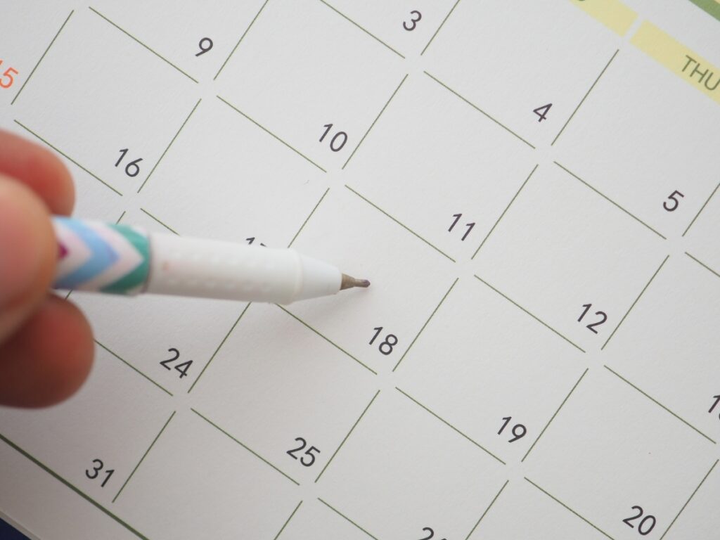 Utility Disconnection Guide Before Moving 2 A hand holding a pen points to the 18th day on a calendar page with numbered squares, highlighting an upcoming Utility Disconnection.