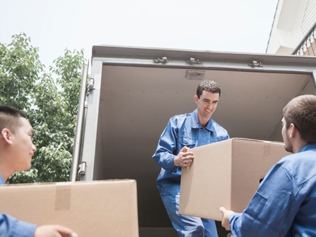 Utility Disconnection Guide Before Moving 5 Three workers in blue uniforms are unloading cardboard boxes from the back of a truck during a utility disconnection operation.